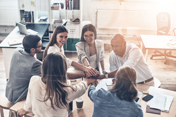 business colleagues holding hands on top of one another in a symbol of unity while working