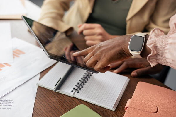Team members' hands reviewing data on a digital tablet, planning and discussing work